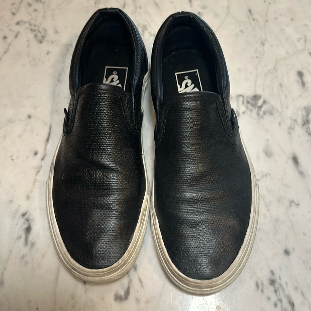 Vans slip on black leather textured sneakers.